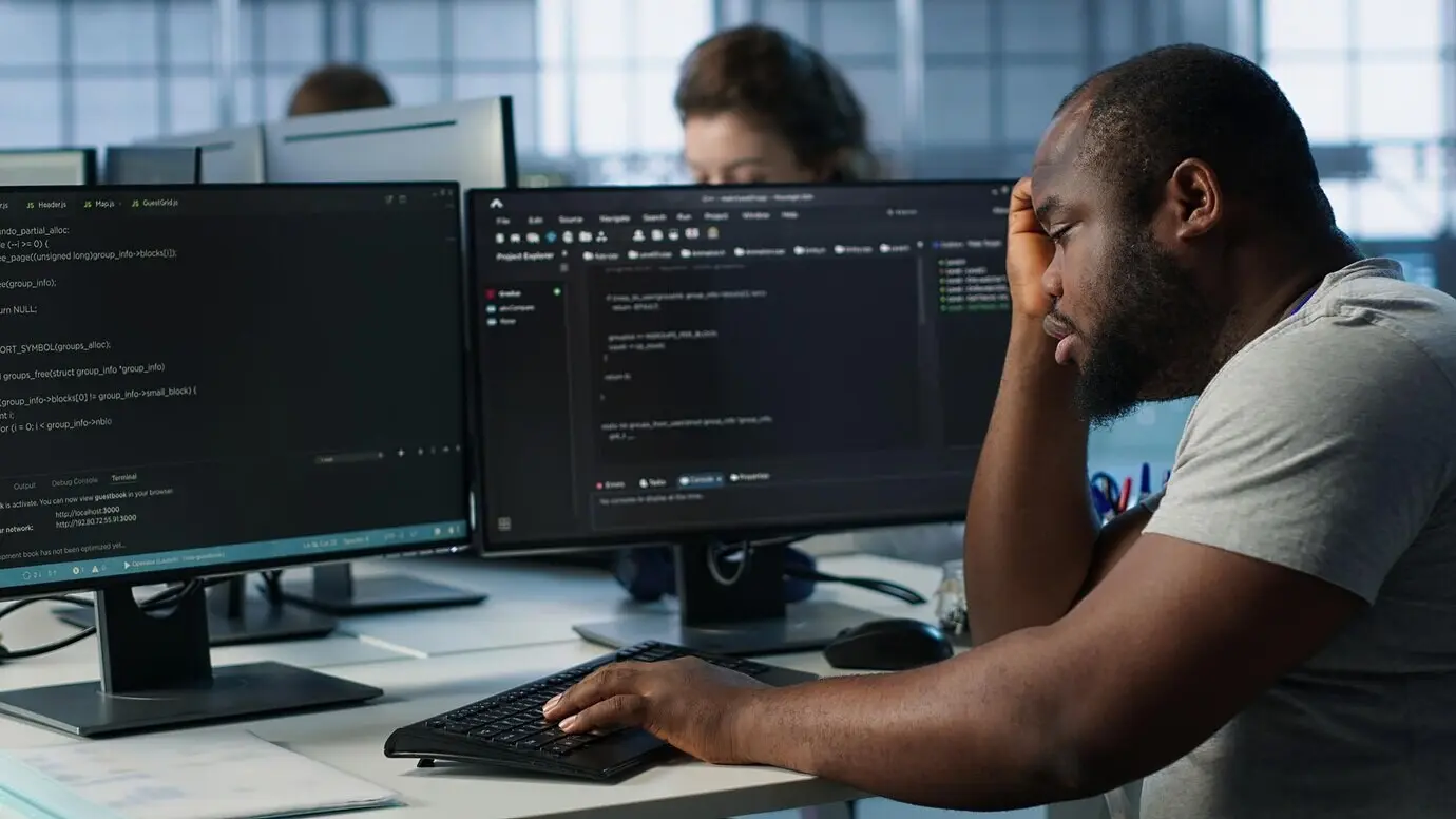 Переутомлённый инженер засыпает, набирая текст на компьютере в серверном хабе.